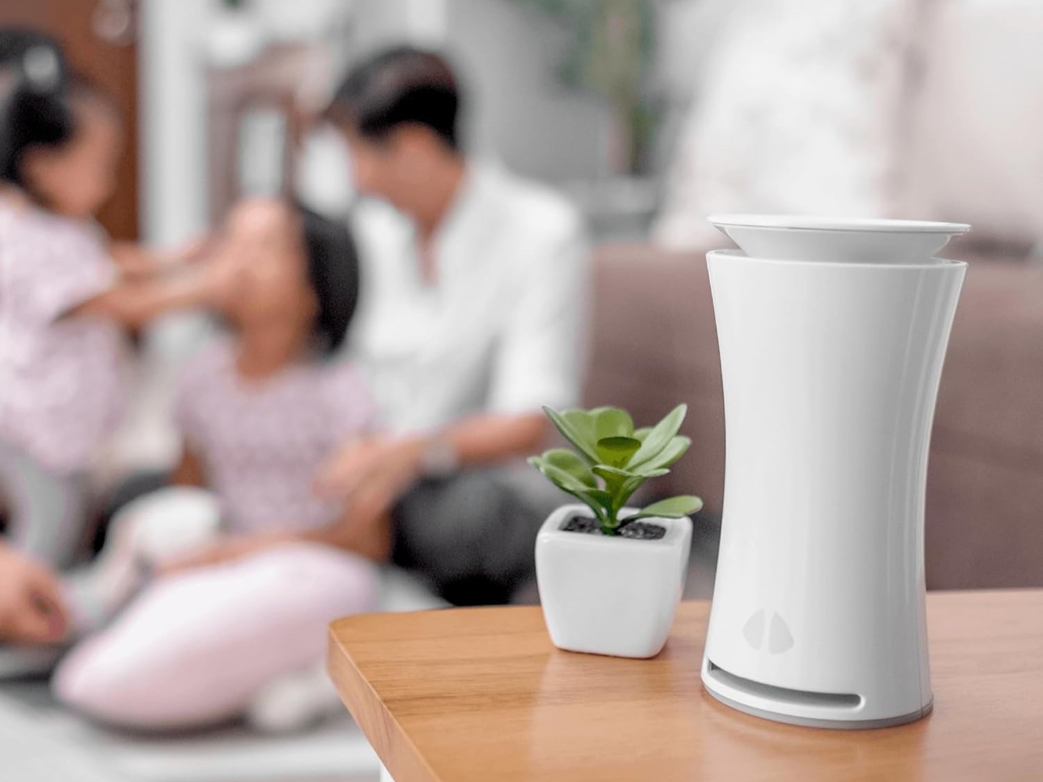 uHoo Smart Air Monitor on table with family in background