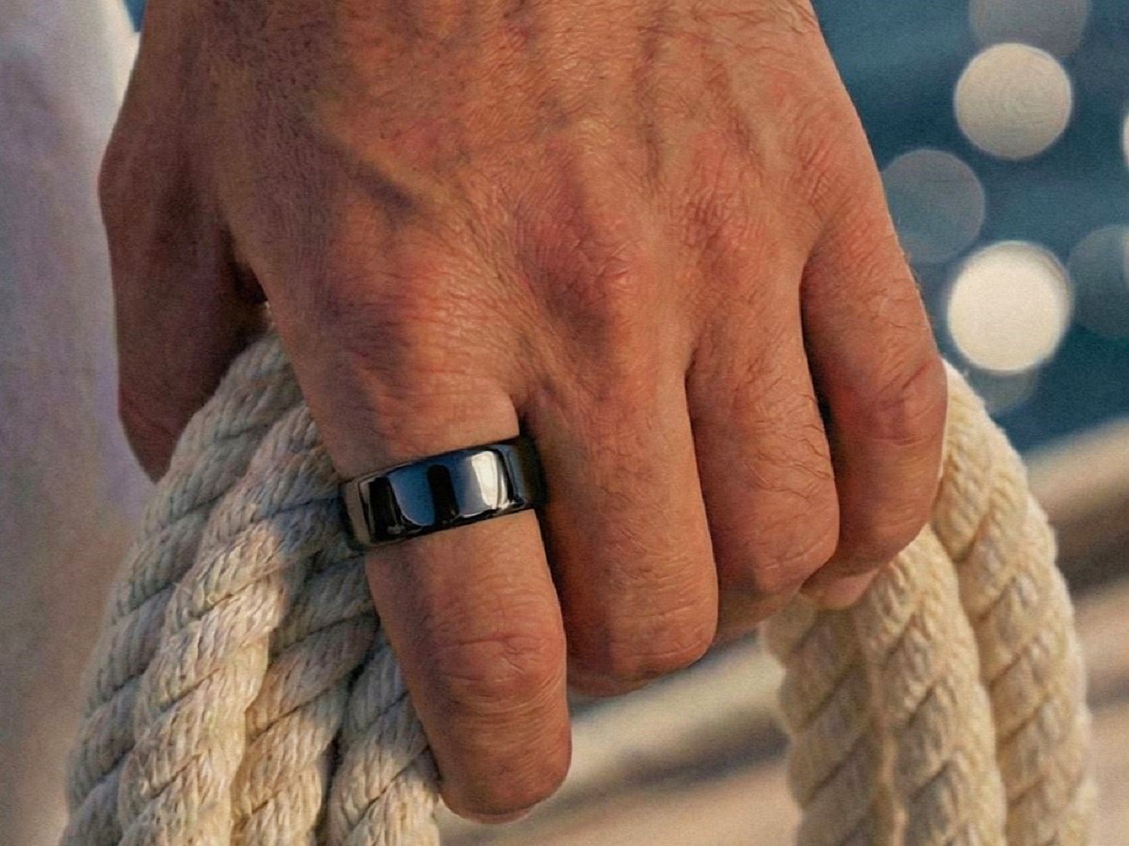 Ultrahuman Ring Pro smart ring worn on finger holding a rope by the water